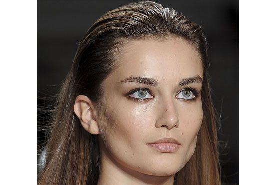 Modelo desfila com cabelo com efeito molhado.