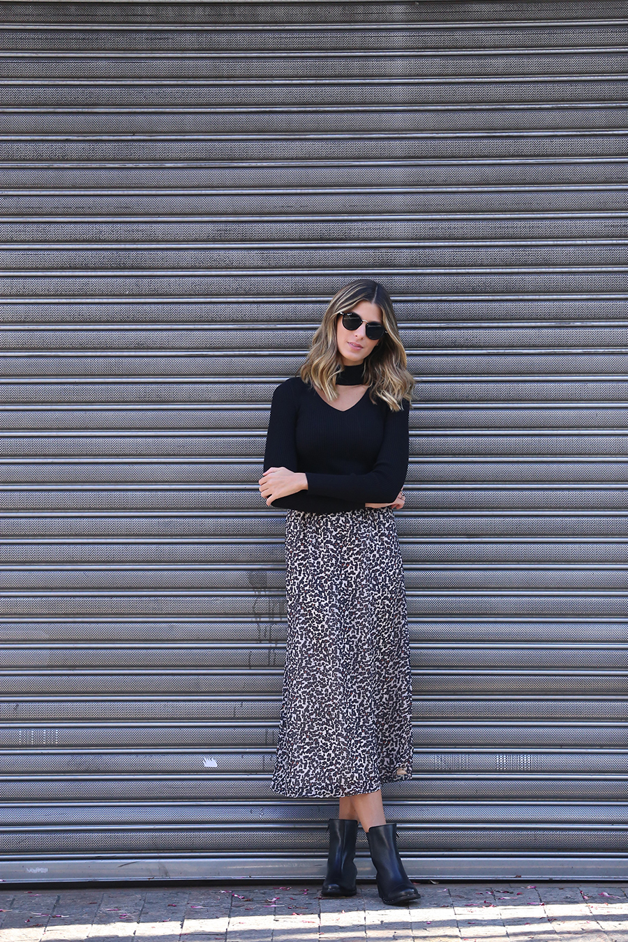 Look blusa choker preta manga longa, com saia longuete de oncinha e bota preta