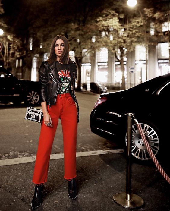 Look camiseta de banda, jaqueta de couro, calça vermelha e bota verniz