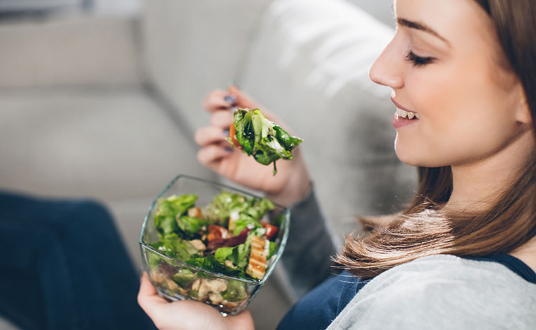 mulher degustando um prato de salada