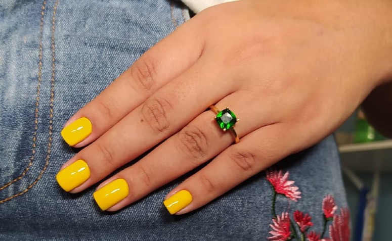 A Criança Senta-se À Mesa E Pinta As Unhas Com Esmalte Amarelo