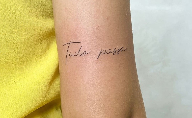 Lettering tattoo that says tudo passa located on the