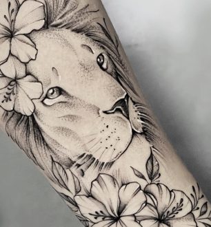 Tatuagem de leão com flores harmoniza força e feminilidade